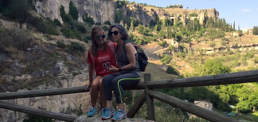 Two students sitting on rail in front of mountain,