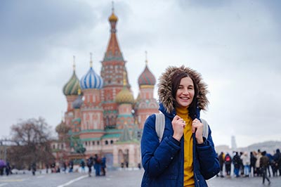 Female in coat standing in front of castle.