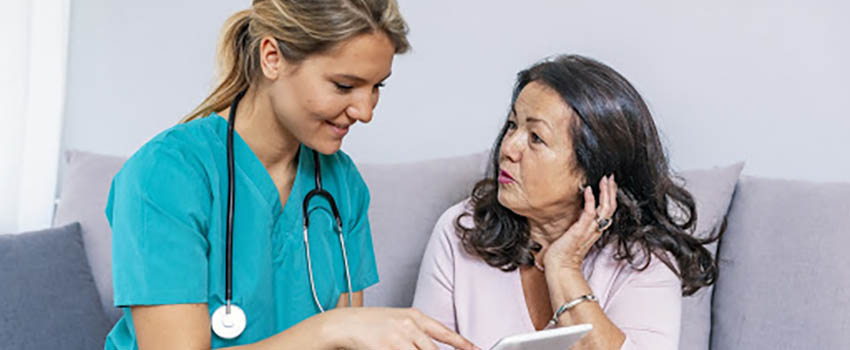 Healthcare worker with stethoscope talking to Spanish woman.