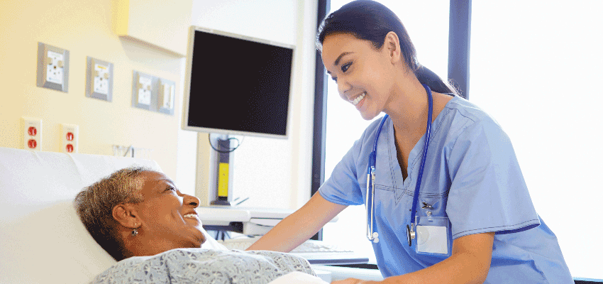 Nursing student working with patient in hospital bed.