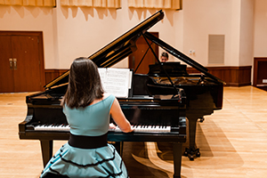 Students playing piano on stage.