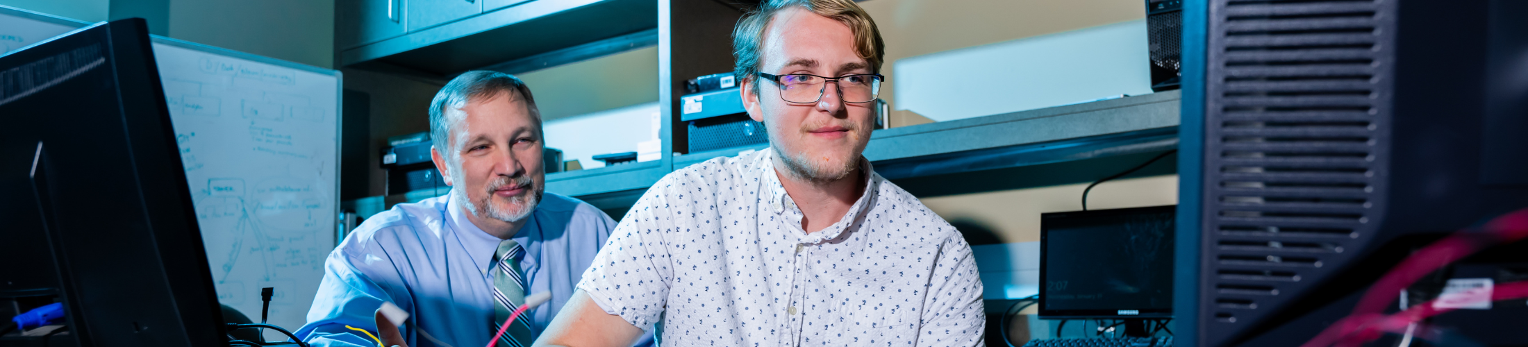 Professor working with student in computer lab.