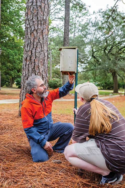 Professor pointing to bottom of birdfeeder.