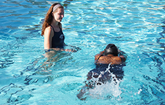 Instructor watching student swim in pool.