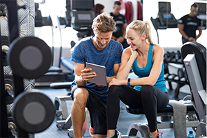 Trainer worker with customer in weight room.