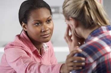 Woman touching another woman's shoulder to show she is caring.