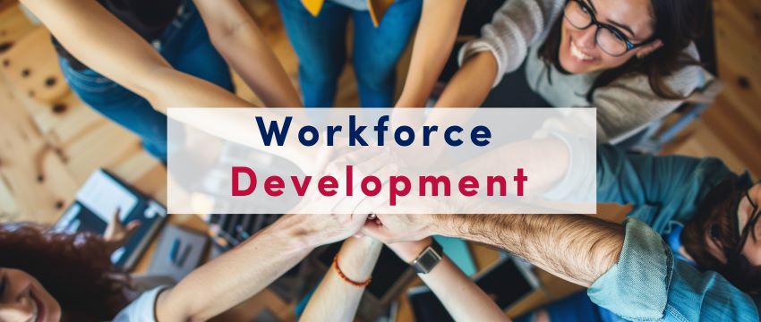 People gathered around with their hands up and a workforce development banner over the picture