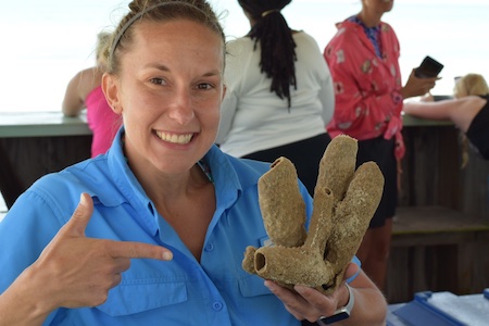 photo of Molly pointing to a large piece of coral in her hand