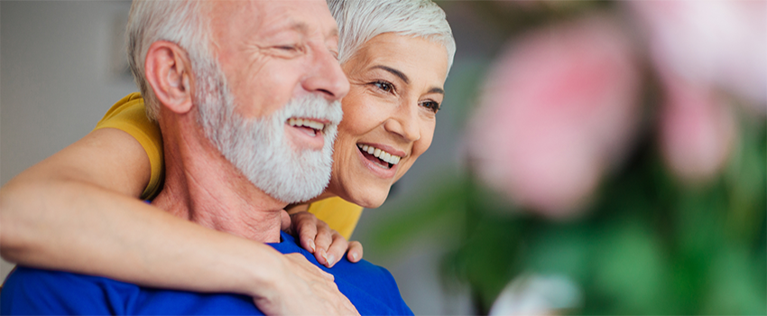 An older couple smiling and hugging.